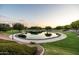 Scenic view of the community pond surrounded by walking paths, lush greenery, and mature trees at 3022 E Santa Fe Ln, Gilbert, AZ 85297
