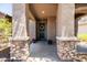 Inviting covered front porch with stone pillars, decorative wreath on the front door, and potted flowers at 3022 E Santa Fe Ln, Gilbert, AZ 85297