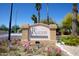 The Raven Condominiums sign with flowers and palm trees under a bright blue sky at 3434 E Baseline Rd # 126, Phoenix, AZ 85042