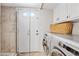 Functional bathroom with an exterior door, tile flooring, and a neatly arranged washer and dryer setup at 538 W Las Palmaritas Dr, Phoenix, AZ 85021