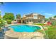 Beautiful backyard featuring a pool, travertine patio, lush landscaping, and a well-maintained lawn at 5431 E Piping Rock Rd, Scottsdale, AZ 85254