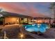 Beautiful backyard with a refreshing pool, covered patio, outdoor seating, and warm ambient lighting at 16077 W Anasazi St, Goodyear, AZ 85338