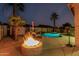 Resort-style backyard featuring a luxurious pool, a warming fire pit, and lush tropical landscaping at 16077 W Anasazi St, Goodyear, AZ 85338