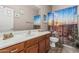 This bathroom features a patterned shower curtain, a mirror, and a single sink vanity with brown cabinets at 16077 W Anasazi St, Goodyear, AZ 85338