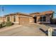 Home's front exterior features a spacious garage, complemented by desert landscaping and a tile roof at 16077 W Anasazi St, Goodyear, AZ 85338