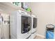 This laundry room features a full-sized white washer and dryer set with some shelving at 16077 W Anasazi St, Goodyear, AZ 85338