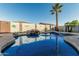Sparkling blue pool features a rock waterfall and mature palm trees, offering a tranquil backyard oasis at 16077 W Anasazi St, Goodyear, AZ 85338