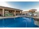 Relaxing backyard pool area with covered patio, outdoor seating, barbecue, and tanning chairs at 16077 W Anasazi St, Goodyear, AZ 85338