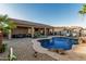 Relaxing pool with rock waterfall, tanning ledges, and a covered patio with outdoor seating, ideal for backyard entertaining at 16077 W Anasazi St, Goodyear, AZ 85338
