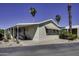 Cozy single-story home with carport and landscaped yard featuring palm trees, under a sunny blue sky at 17200 W Bell Rd # 1602, Surprise, AZ 85374