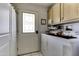 Laundry room with a washer, dryer, and overhead cabinets next to exterior door at 17200 W Bell Rd # 1602, Surprise, AZ 85374