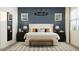 Beautiful bedroom with blue accent wall, large bed, neutral colored carpet, and modern lighting at 17473 W Victory St, Goodyear, AZ 85338