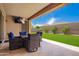Inviting covered patio features outdoor dining and views of the manicured backyard with verdant lawn and mature palms at 18334 W Marshall Ln, Surprise, AZ 85388