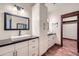 Bathroom featuring dual sinks with black countertops, white cabinetry, and hardwood floors at 2602 S 226Th Dr, Buckeye, AZ 85326