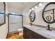 Bathroom featuring dual sinks, a walk-in shower, and wooden look floors at 2602 S 226Th Dr, Buckeye, AZ 85326