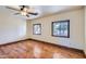 Bright bedroom featuring hardwood floors, two windows and a ceiling fan at 2602 S 226Th Dr, Buckeye, AZ 85326