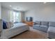 Bright bedroom features a large window, comfortable bed, sofa, and a modern dresser with TV at 26774 W Firehawk Dr, Buckeye, AZ 85396