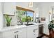 Bright, modern kitchen features white cabinets, marble countertops, black hardware, and a view to the backyard at 4525 N 66Th St # 1, Scottsdale, AZ 85251