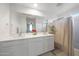 Bathroom featuring double sinks, a large mirror, white cabinets, and a shower at 5439 W Odeum Ln, Phoenix, AZ 85043