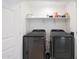 Convenient laundry room featuring modern black appliances, storage shelves, and efficient functionality at 5439 W Odeum Ln, Phoenix, AZ 85043
