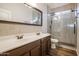Bathroom featuring a double vanity, decorative mirror, and glass enclosed shower at 760 N Swallow Ln, Gilbert, AZ 85234