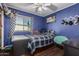 This bedroom has a plaid comforter, blue walls, and a window for natural light at 8415 W Coolidge St, Phoenix, AZ 85037