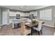Open-concept kitchen flowing into the dining area, featuring a granite island, stainless appliances, and white cabinetry at 10556 W Bloch Rd, Tolleson, AZ 85353