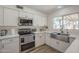 Well-lit kitchen with modern stainless steel appliances, quartz countertops, and a view from the window at 12234 S Pewaukee St, Phoenix, AZ 85044