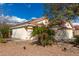 Single story beige home with red clay roofing and front yard desert landscaping with blue skies and scattered clouds at 13864 W Ironwood St, Surprise, AZ 85374