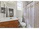 Bathroom with a wooden cabinet vanity, white sink, toilet, and shower with patterned curtain at 14621 W Catalina Dr, Goodyear, AZ 85395