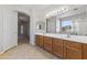 Bright bathroom features a double sink vanity with wooden cabinets and a large mirror at 14621 W Catalina Dr, Goodyear, AZ 85395