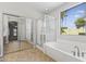 Bright bathroom with a glass shower, large window, garden tub, and mirrored closet doors at 14621 W Catalina Dr, Goodyear, AZ 85395