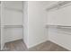 Walk-in closet features neutral carpet, baseboards, and multiple white shelves at 14621 W Catalina Dr, Goodyear, AZ 85395