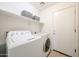 Functional laundry room with modern washer and dryer and ample shelf space for storage at 15537 W Port Royale Ln, Surprise, AZ 85379