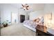 Large main bedroom boasting plush carpet, a ceiling fan, and a well-lit space with a doorway to the ensuite bathroom at 15537 W Port Royale Ln, Surprise, AZ 85379