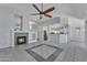 Open living room with fireplace, ceiling fan, tile floors, and view of kitchen at 18088 W San Alejandro Dr, Goodyear, AZ 85338