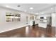Bright, open-concept living room showcasing dark hardwood floors and modern white kitchen with stainless steel appliances at 1911 E Lawrence Rd, Phoenix, AZ 85016