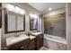 Bathroom with dual vanities, granite countertops, and bathtub with tiled surround at 2006 W Gold Dust Ave, Queen Creek, AZ 85144