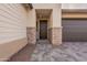 Covered front entry featuring stone accents, neutral stucco, and a modern garage door at 21411 W Meadowbrook Ave, Buckeye, AZ 85396