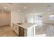 Open kitchen with quartz countertop island, white cabinets, stainless appliances, and wood-style tile flooring at 21411 W Meadowbrook Ave, Buckeye, AZ 85396