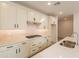 Modern kitchen features white cabinets, quartz countertops, stainless steel appliances, gas cooktop, and wood-style tile flooring at 21411 W Meadowbrook Ave, Buckeye, AZ 85396