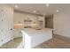 Bright kitchen features white cabinets, island with quartz countertop, stainless steel sink, and wood-style tile flooring at 21411 W Meadowbrook Ave, Buckeye, AZ 85396