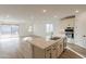 Bright, open-concept kitchen with island, white cabinets, stainless appliances, quartz countertop, and wood-style tile flooring at 21411 W Meadowbrook Ave, Buckeye, AZ 85396