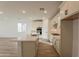 Open kitchen features white cabinets, quartz countertops, stainless appliances, an island, and wood-style tile flooring at 21411 W Meadowbrook Ave, Buckeye, AZ 85396