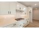 Modern kitchen boasts white cabinets, quartz countertops, stainless steel appliances, gas cooktop, and wood-style tile flooring at 21411 W Meadowbrook Ave, Buckeye, AZ 85396