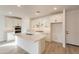 Spacious kitchen with white cabinets, stainless appliances, quartz countertop island, and wood-style tile flooring at 21411 W Meadowbrook Ave, Buckeye, AZ 85396