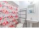 Bathroom featuring a pedestal sink, toilet, and a bathtub with a floral shower curtain at 3115 N 55Th Ave, Phoenix, AZ 85031