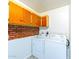 Practical laundry area with brick accent wall, upper cabinets, and washer/dryer at 3115 N 55Th Ave, Phoenix, AZ 85031