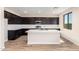 Modern kitchen featuring an island, stainless steel appliances, dark cabinets, and wood-look tile flooring at 31850 N Bandit Rd, San Tan Valley, AZ 85143