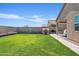 Lush backyard with green lawn, privacy fence, and patio area with cover; a cute playhouse sits by the patio at 3597 E Henson St, San Tan Valley, AZ 85140